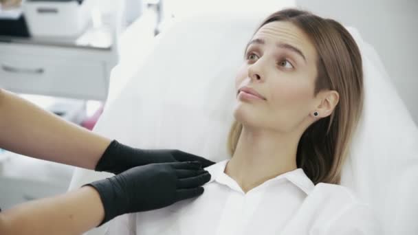 Крупным планом молодая женщина показывает косметологические участки на лице для инъекций и лечения — стоковое видео
