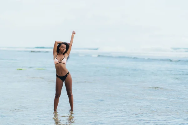 美丽的深色皮肤的女孩在泳衣休息在海滩上。在热带岛屿上摆姿势的非裔美国人模型 — 图库照片