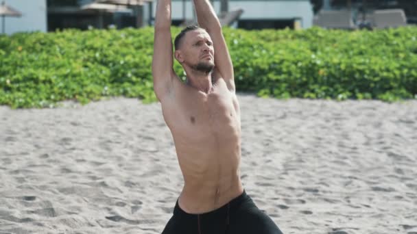 모래 해변에서 요가 포즈와 필 라 테 스 운동을 하 고 운동 남자 — 비디오