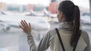 Yakın çekim arka görünümü havaalanında uçak arka plan üzerinde pencere bakarak sırt çantası ile kızın