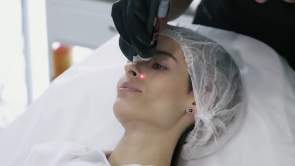 Primer plano cosmetólogo con equipo especial hace procedimiento láser para la extracción de los vasos sanguíneos en la cara niñas . — Vídeos de Stock