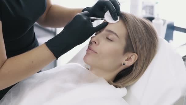 Close-up mulheres rosto e cosmetologists mãos com seringa faz injeções de beleza facial . — Vídeo de Stock