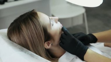 Yakın çekim yan görünümü kadının yüzü ve kozmetik eller şırınga yapar yüz güzelliği enjeksiyonları ile