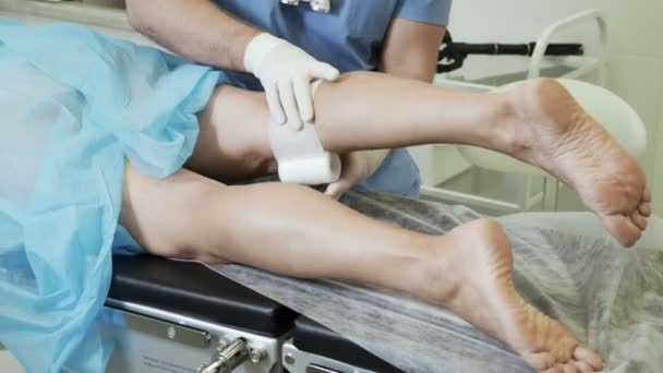 Phlebologist eldiven yakın çekim elinde bandaj bacağında skleroterapi işlemden sonra koymak — Stok video