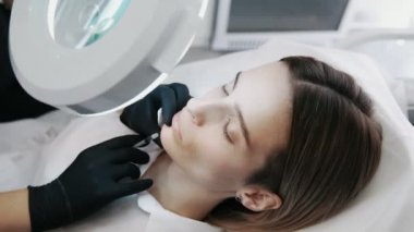 Güzellik uzmanı şırınga ile yakından kadın enjeksiyonları yapar ve kozmetik Büyüteç görünüyor