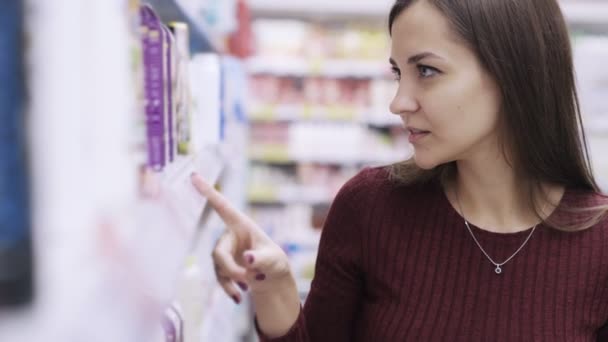 Portrét krásné ženy při pohledu na cenovky a hledáte produkt v supermarketu. — Stock video