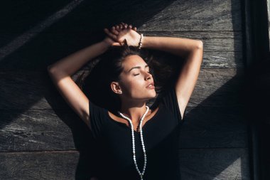 Ahşap yerde yatarken siyah elbiseli güzel seksi kız portresi üstten görünüm