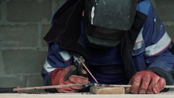 De cámara lenta, soldador en la máscara de soldadura suelda dos piezas de metal. Trabajador en mono está trabajando en el interior — Vídeo de stock