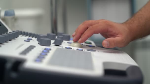 Закрыть руки врача нажимает кнопки и работает на ультразвуковом устройстве . — стоковое видео