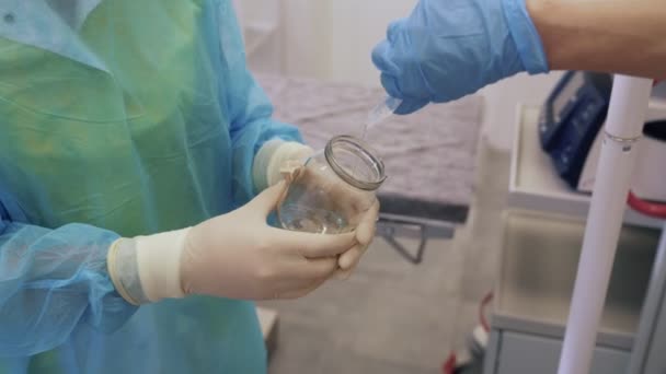 Gros plan du médecin verse le désinfectant dans un bocal en verre tenu par une infirmière — Video