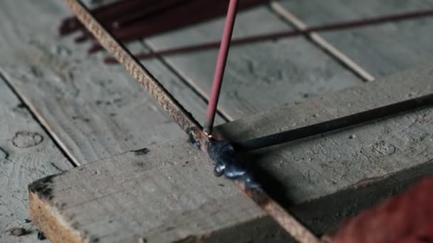 Nahaufnahme, Schweißer schweißt zwei Metallteile. Arbeiter in Overall arbeitet drinnen — Stockvideo