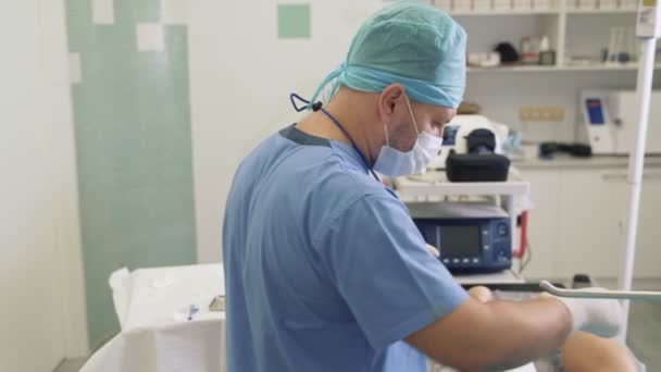 Arzt in sterilen Handschuhen desinfiziert Patientenbein und bereitet medizinisches Werkzeug vor Krampfadern-Operation vor — Stockvideo