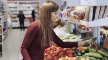 Genç kız sebze süpermarket alışveriş bölümünde satın alır ve onları plastik torbaya koyar