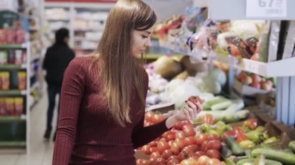 Jong meisje fruit in supermarkt departement van supermarkt koopt en zet ze in een plastic zak — Stockvideo