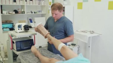 Cerrah skleroterapi işleminden sonra hasta bacağında sıkıştırma çorap koyar