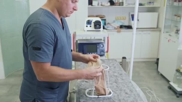 Ο γιατρός προετοιμάζει τις κάλτσες συμπίεσης και την τοποθετεί σε ειδική κατασκευή πριν από τη χειρουργική επέμβαση — Αρχείο Βίντεο