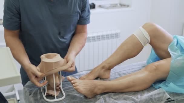 Chirurgo mette su stoccaggio di compressione sulla gamba paziente dopo l'operazione di scleroterapia — Video Stock