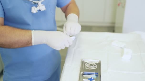 Крупным планом врач в стерильной одежде и перчатках готовит медицинские инструменты перед операцией — стоковое видео