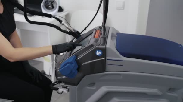 Zijaanzicht artsen handen in handschoenen draait laserapparatuur voor epilatie procedure, Slow-Motion. — Stockvideo