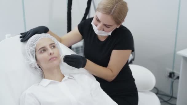 Pomalý pohyb beauticijky v jednorázové masce připraví pacienty pro kosmetické postupy, léčbu — Stock video