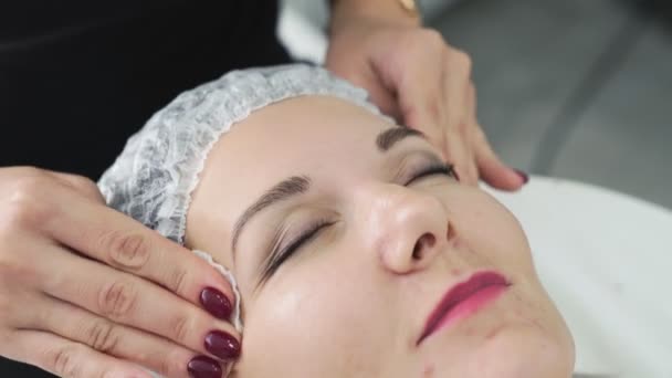 Primer plano cosmetólogo limpia la piel de la mujer con almohadillas de algodón húmedo antes del procedimiento de cuidado facial — Vídeos de Stock