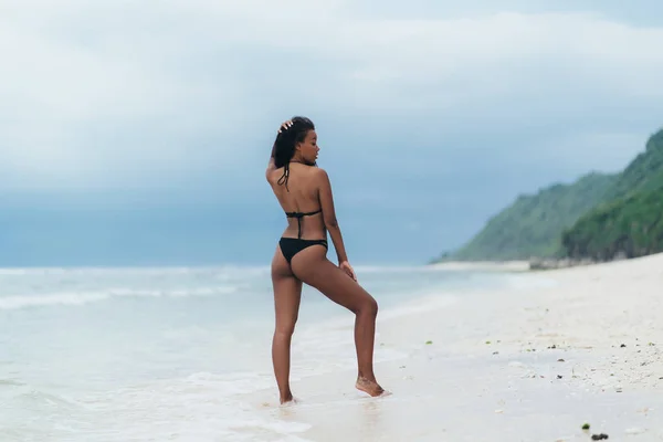 Πίσω όψη σέξι αφροαμερικάνικη γυναίκα αναπαύσεως και ηλιοθεραπεία στο νησί παράδεισος. — Φωτογραφία Αρχείου