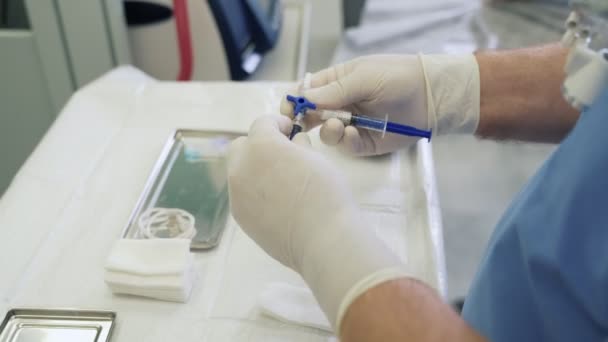 Крупным планом руки врача в стерильных перчатках готовят медицинские инструменты для склеротерапии — стоковое видео