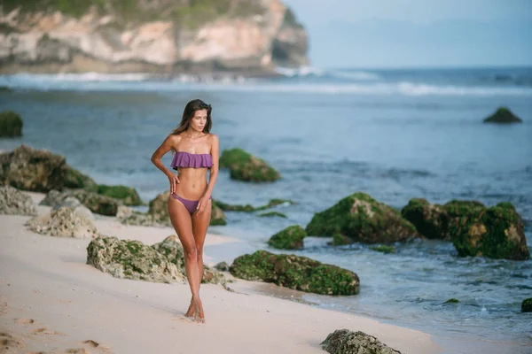 Menina sexy em maiô cor roxa posando no dia ensolarado na praia de areia — Fotografia de Stock