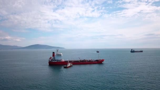 Su üzerinde kırmızı tanker gemisi havadan görünümü, yakın çekme gemisi, limana giriş — Stok video