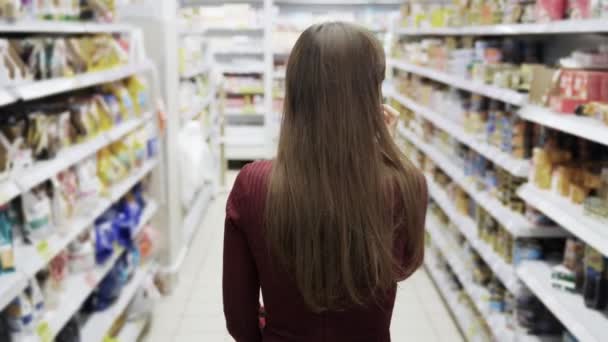 Vista trasera, mujer de compras en el supermercado, toma steadicam . — Vídeo de stock
