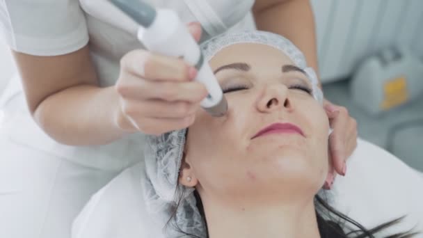 Le cosmétologue fait une procédure anti-âge et de levage sur le visage de la femme à la clinique, au ralenti — Video