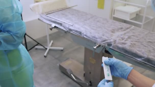 Las enfermeras en guantes estériles y ropa preparan jeringas y agujas antes de la cirugía de escleroterapia — Vídeo de stock
