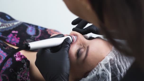 Руки крупным планом косметолога делают процедуры гидроочистки лица и пилинга на женском лице — стоковое видео
