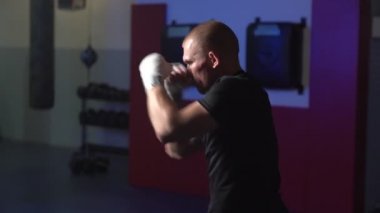 Düşük ışık sahne, boksör adam spor salonunda ısınma, yavaş hareket eğitim sürecinin yan görünümü.