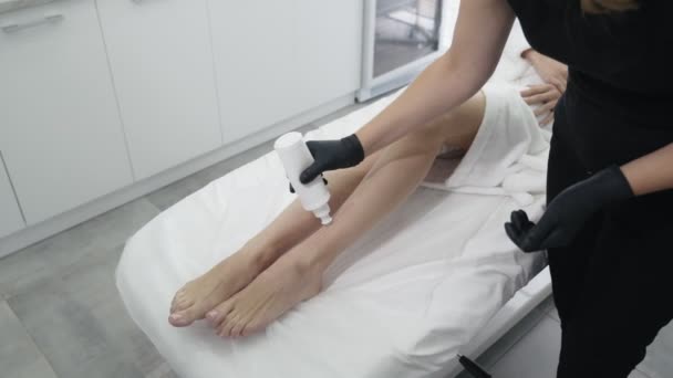 Закрыть руки врача в перчатках наносит гель на ногу пациента перед лазерной процедурой удаления волос, замедленное движение — стоковое видео