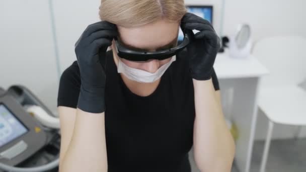 El médico cosmetólogo de cámara lenta se pone gafas protectoras especiales antes del procedimiento. — Vídeos de Stock