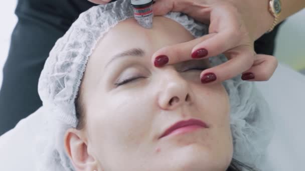 Gros plan Les mains du cosmétologue effectuent des interventions sur le visage du patient avec un dispositif d'hydropelage, au ralenti — Video