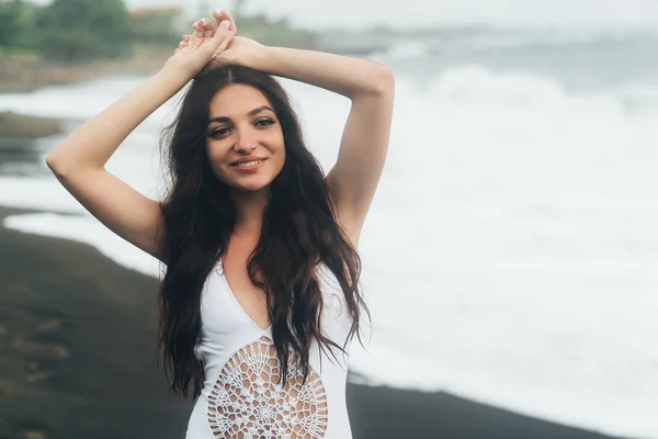 Retrato de chica feliz con hermosa sonrisa en traje de baño posando en la playa de arena negra —  Fotos de Stock