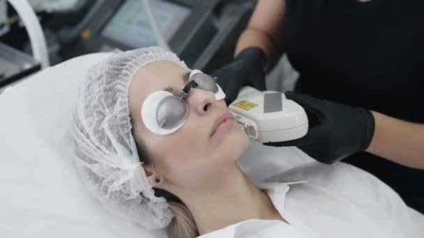 Slow Motion cosmetoloog maakt meisje procedure voor genezing huid van gezicht met speciaal apparaat — Stockvideo