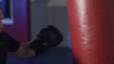 Yakın çekim, boks eldiveni ile bir kum torbası tekme, yavaş hareket boksör eğitim