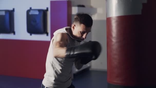 Boxer homem trabalhando golpes em um saco de perfuração em câmera lenta, vista lateral . — Vídeo de Stock