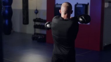 Backside view boksör egzersizleri yapar, kollarında kasları ısıtıyor ve mücadele için hazırlar, yavaş hareket.