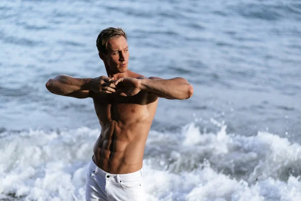 Hermoso hombre con el torso muscular desnudo en la playa de arena blanca . — Foto de Stock