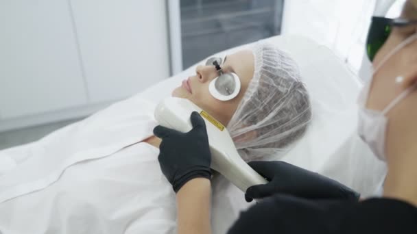 Cosmetologist de movimento lento faz o procedimento de menina para hidratar a pele do rosto com o dispositivo especial — Vídeo de Stock