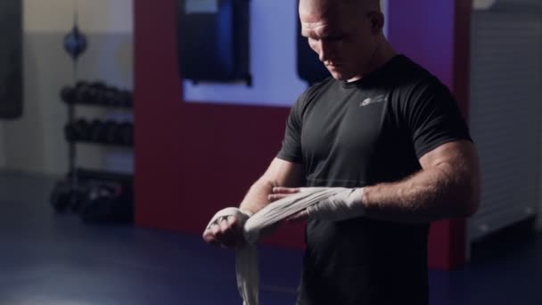 Жестокий боксер, заворачивающий руки эластичными бинтами перед боем, замедленная съемка. Сцена низкой освещенности — стоковое видео