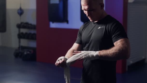 Boxer brutal que envolve mãos com ataduras elásticas antes da luta, câmera lenta. Cena de luz baixa — Vídeo de Stock