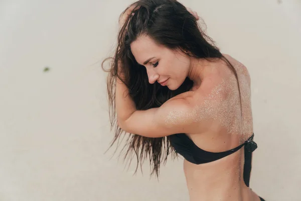 Beautiful model in black swimsuit posing on white sandy beach — Stock Photo, Image