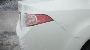 Araba yıkama. Yüksek basınçlı su jeti kirli beyaz arabayı temizleyin. Yavaş çekim