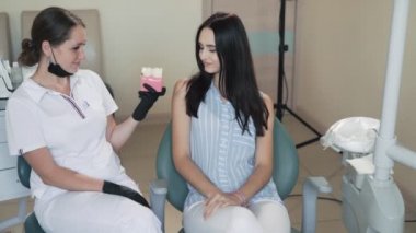Diş hekimi çürük ve sağlıklı diş, yavaş hareket ile diş hasta modeli gösterir