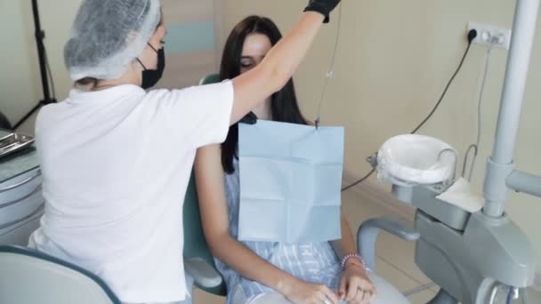 Dentista coloca guardanapo no paciente antes do tratamento dentário, câmera lenta. Steadicam tiro — Vídeo de Stock